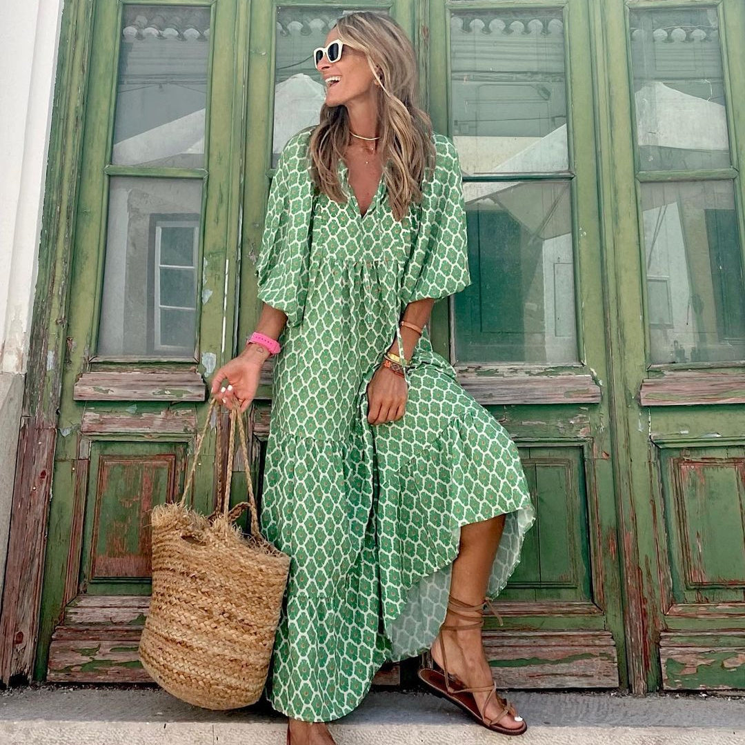 A woman in a summer bohemian v-neck dress stands by green doors, showcasing a flowy silhouette and boho-inspired design.